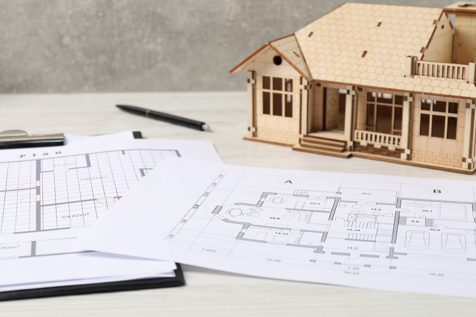 Ghost Drafters real estate. house model and floor plan on white wooden table, closeup